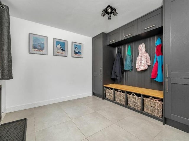 Recently added to the ground floor of the property is this ingenious boot room. or cloakroom. It is fitted with a range of solid-wood shaker-style wall units and inset central bench, plus ceiling lights and a column radiator.
