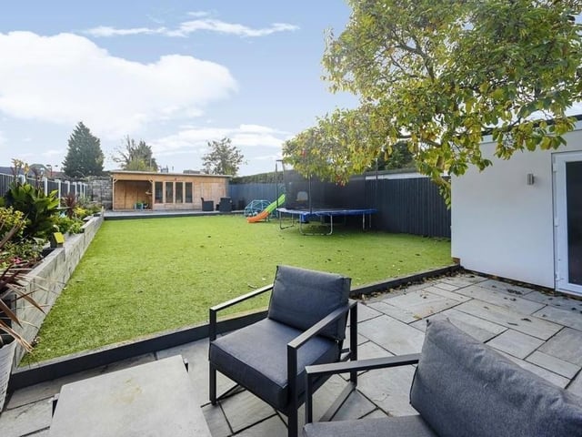 The last image in our photo gallery captures the large, enclosed, landscaped garden at the back of the property. In the foreground is a patio seating area, in the background is a garden cabin that could be used as a multi-purpose room, and in between is an artificial lawn, where the kids can play happily.