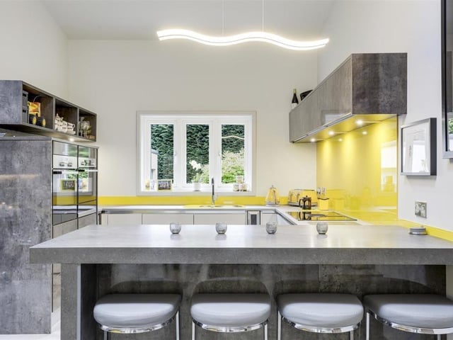 The glossy and classy kitchen has a range of fitted base and wall units with worktops and a breakfast bar, plus an inverted stainless steel sink and a half with a swan-neck mixer tap and drainer.