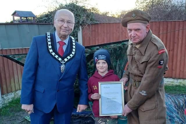 Coun Tom Munro, left, watches as Tommy is presented with a certificate of achievement.
