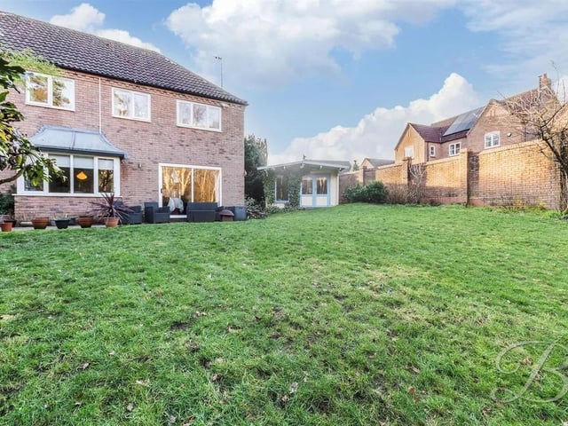 The rear garden is exceptionally spacious, featuring a manicured lawn, a patio area, and mature shrubs and trees. This impressive outdoor space is ideal for entertaining, family recreation, or simply enjoying the peaceful surroundings.