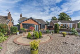 To the front, a large stone garden and patio sit alongside a spacious driveway