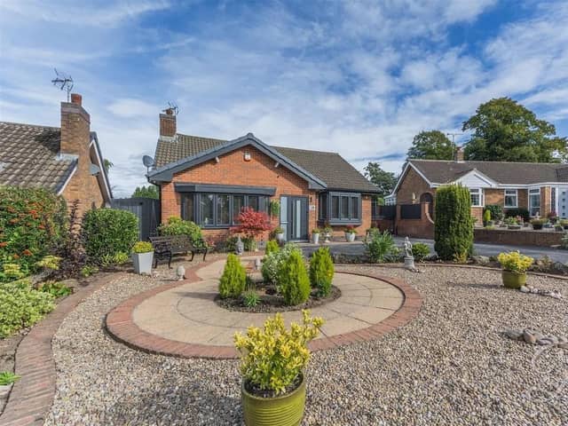 To the front, a large stone garden and patio sit alongside a spacious driveway