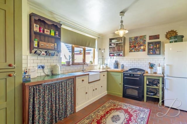 From the hallway, we move into the brilliant and busy kitchen, which is fitted with shaker-style cabinets, complemented well by a Belfast sink and tiling.