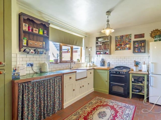 From the hallway, we move into the brilliant and busy kitchen, which is fitted with shaker-style cabinets, complemented well by a Belfast sink and tiling.