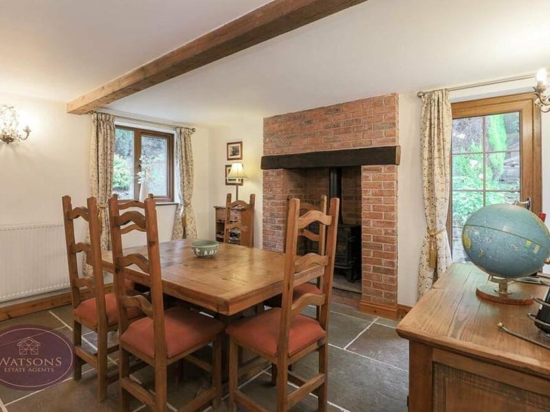Moving into the dining room now. It is another room with a wealth of traditional features, including an inglenook fireplace with an inset multi-fuel burner, slate tiled flooring and exposed ceiling beams. One door leads outside and another to the study.