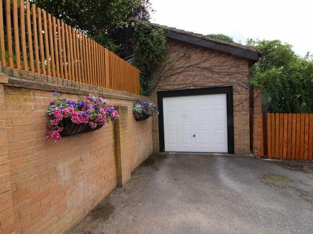 A detached garage, with an up-and-over door and eaves storage, sits at the end of a private, gated driveway that provides space for off-street parking.