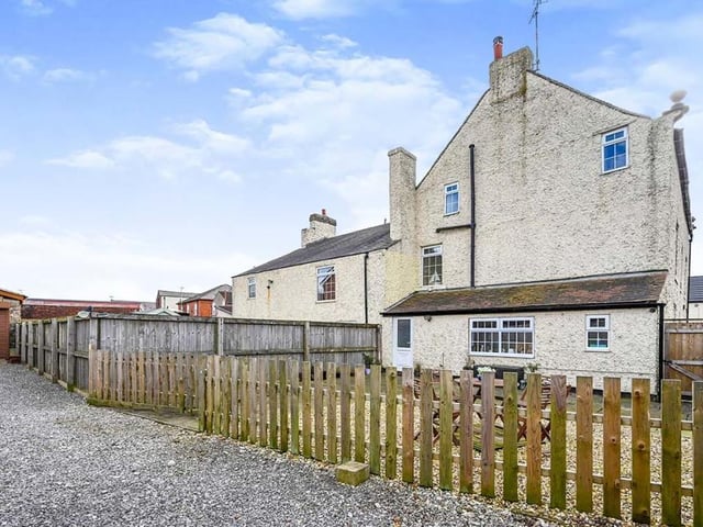 This view from the rear of the property shows a shared driveway that leads to a double garage with electronic up-and-over doors. The enclosed back garden is paved and easy to maintain, with space for a seating area.