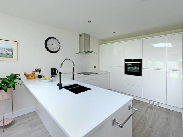 Integrated appliances in the sleek kitchen include an oven, induction hob with extractor and a fridge freezer. The whole layout is beautifully presented, with underfloor heating and a stylish, grey laminate floor.