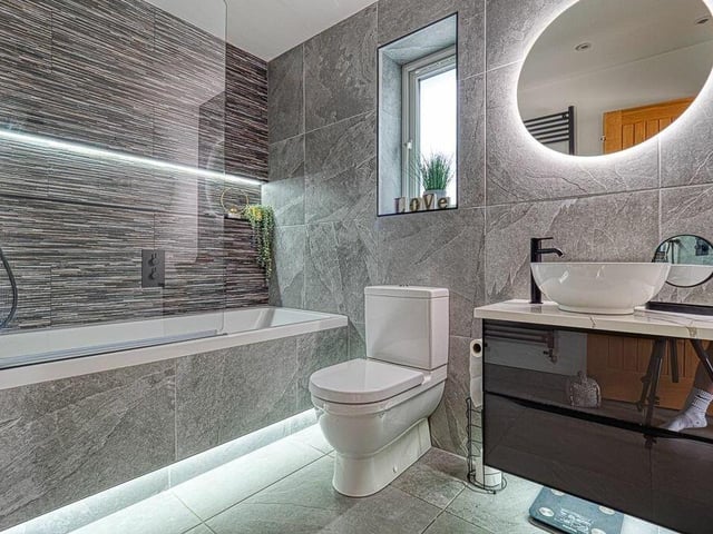 The sparkling family bathroom has been completely remodelled. It is now fitted with motion-sensor mood lighting, additional LED spotlights, bath with matt black taps, drench power shower,  wash hand basin with vanity unit, a low-level toilet, tiled floor, heated towel-rail and store cupboard.