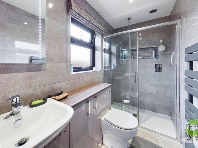 This is the sparkling en suite bathroom to the master bedroom. It is fully tiled and boasts a shower cubicle, hand wash basin, WC and storage units.