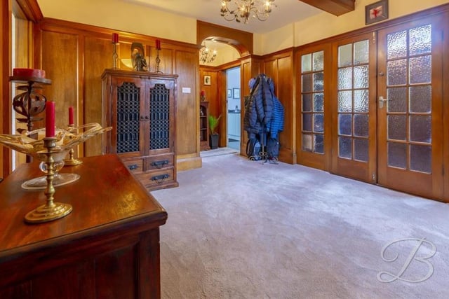 The sizeable entrance hall is warm and welcoming, with solid oak panelled walls and a carpeted floor.