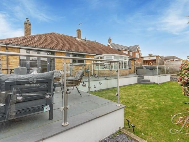 Beyond the raised patio in the back garden, you can just make out a hot tub area.