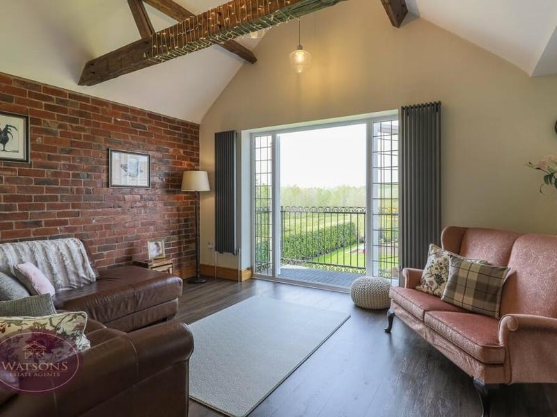 Here is the family room that is part of the open-plan section of the ground floor that also contains the kitchen and dining room. A comfortable corner of the house, it boasts a vaulted ceiling with beams, French doors and a balcony overlooking the rear garden.