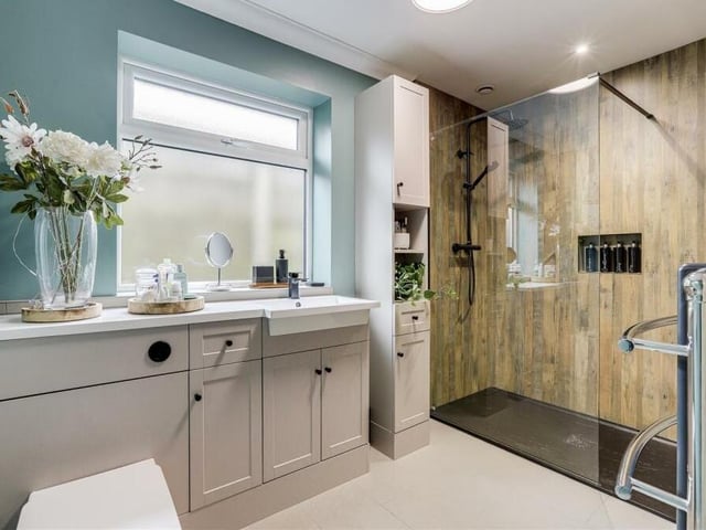 The bathroom, or shower room, has been recently refitted to provide a luxurious, elegant space. A walk-in double shower enclosure features an overhead rainfall shower, a hand-held shower head and a recessed wall alcove. The floor of the room is tiled.