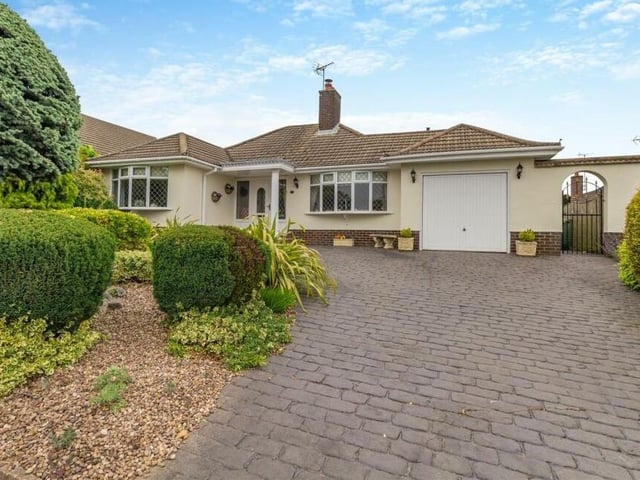 For the last photo in our gallery, we return to the front of the bungalow, where a patterned, block-paved driveway, from gated access, provides off-street parking space and leads to a single garage.To the left is a circular patio with pebbles and a variety of mature plants, shrubs and small trees.