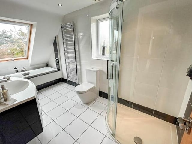 At each end of the first floor sits a contemporary bathroom. Here is one if them, complete with bath, shower cubicle, hand wash basin, storage, WC and chrome, heated towel-rail.