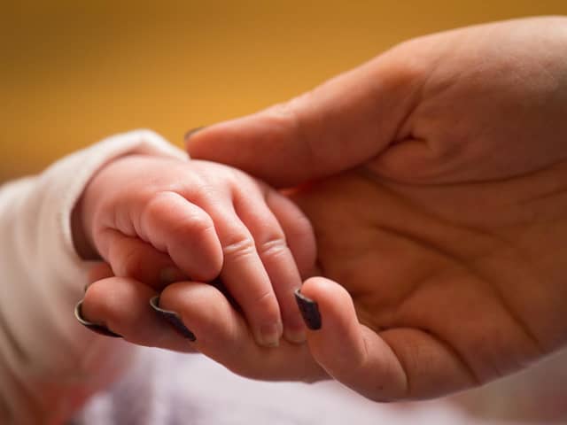A mother holds the hand of a new baby.
