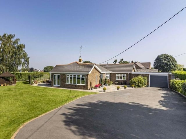 The electric gates open on to a large driveway, which provides off-street parking space for several vehicles and leads to a good-sized garage. A well-maintained lawn completes the frontage.