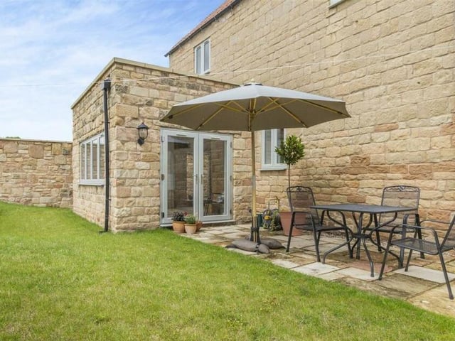 The garden at the £625,000 barn conversion features two stone patio areas, including this delightful one, outside the orangery extension.