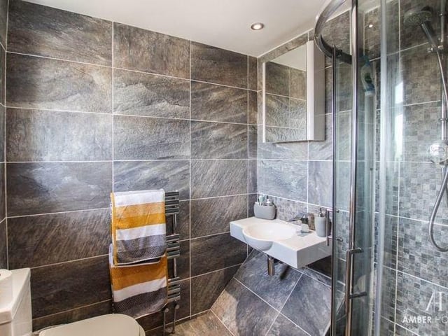 The en suite to the main bedroom is modern and smart. A three-piece suite consists of a walk-in shower cubicle, a wall-mounted wash basin and low-level WC. The floor and walls are tiled, and there is a chrome heated towel-rail.
