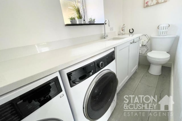 Just off the kitchen/diner is this handy utility room, which has space for a washing machine and tumble dryer. It is fitted with base units and a quartz worktop, while a low-level WC sits at the far end.