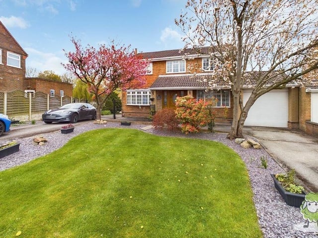 The last photo of our gallery returns to the front of the £995,000 property and shows a twin driveway, lawn and tandem garage.