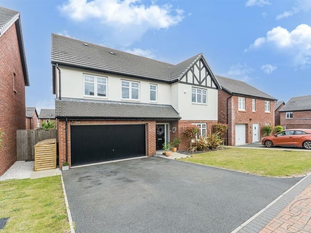 The last photo in our gallery returns to the striking frontage of the property, where a low-maintenance garden features a private driveway that provides off-street parking space and leads to a substantial garage.