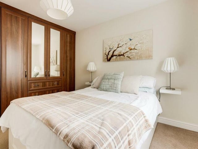 More built-in wardrobes add to the appeal of the second bedroom. The floor is carpeted.