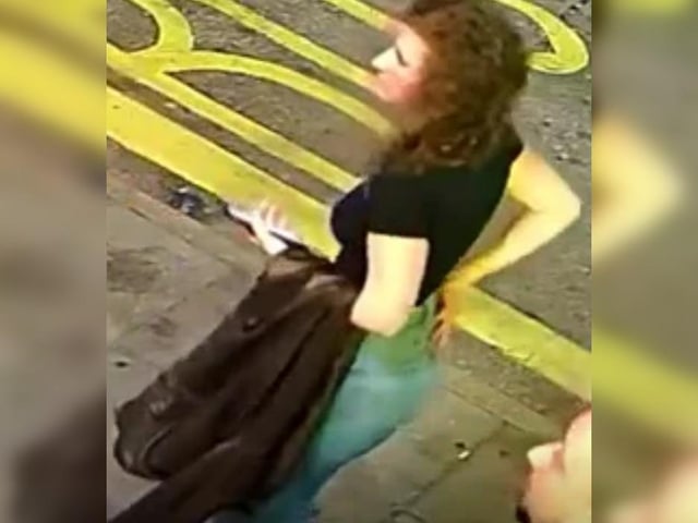 Woman with curly hair, black t-shirt and jeans, carrying a jacket.