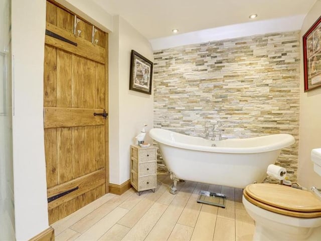 Completing the first floor is this delightful bathroom, with a free-standing bath that has central taps, a hand-held shower head and claw feet. There is also a low-flush WC and wood-effect flooring.