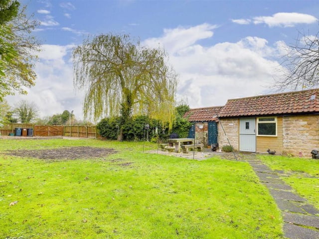 This photo shows the stone-built outhouse from the outside and also gives a good idea of the size of the garden at the back of the £375,000 cottage.