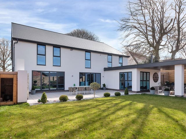 To the rear of property, there is a west-facing, landscaped garden featuring an extensive patio extending the full width of the property and beyond to a large undercover seating area.