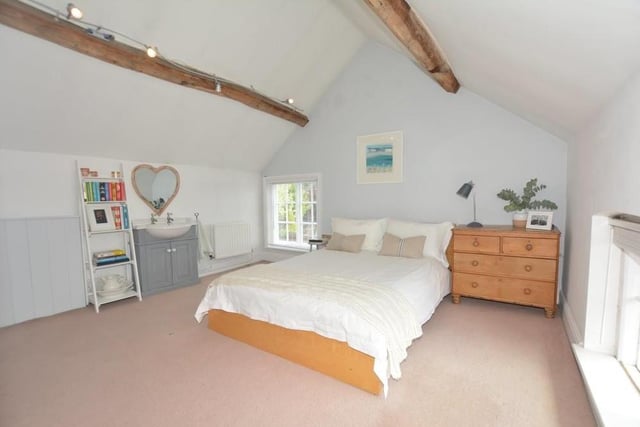 To see the remaining two double bedrooms, let's move up to the third floor. Bedroom number four has a vaulted beamed ceiling and also its own wash hand basin with vanity storage beneath. There are windows to the side and front of the property.