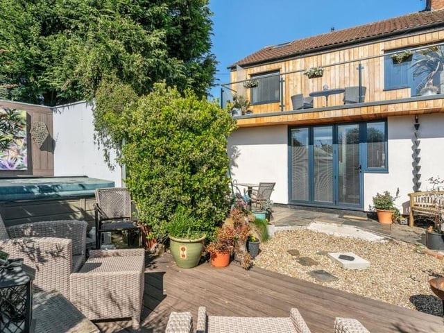 Before we step inside the cottage, here is a view from the private garden at the rear, showing the balcony from the master bedroom that provides stunning countryside views. The garden also features a raised, decked seating area and a partly enclosed hot-tub zone.