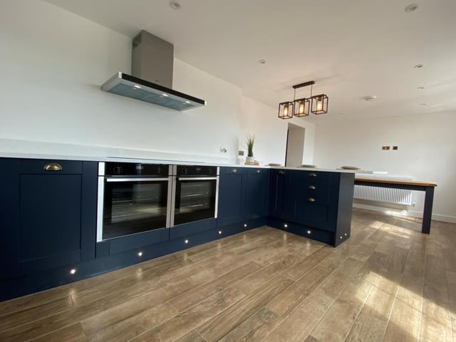 A third photo of the polished and sleek kitchen. There are dual-aspect windows, to the front and side of the house, while a stable door leads out into the landscaped garden