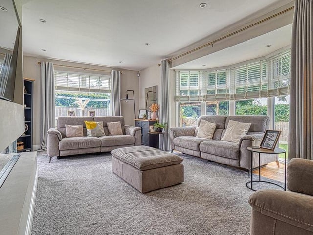 Other assets within the living room include a media wall, panelled decor, LED spotlights and double-glazed French doors leading to the garden.