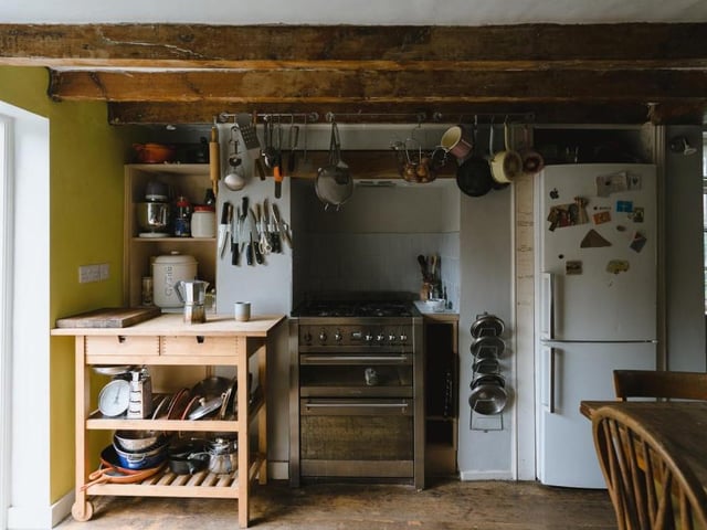 A second shot of the kitchen with its beams overhead and its dining table to the right. Opposite the kitchen is a cellar, located half-a-storey below ground, which functions currently as a pantry and larder.