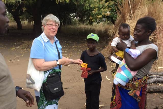 Joan Green pictured in one of the Zambian villages, giving out a blanket and knitted puppet to one of the families. Picture Joan Green