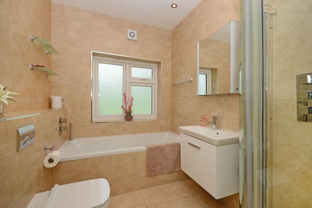 The fully tiled bathroom has a white suite with a separate shower cubicle.