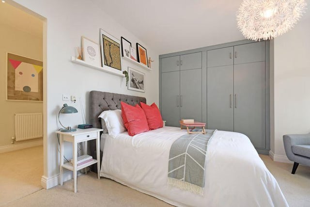 The bedroom has a front bay window and grey-fronted fitted wardrobes - it leads into a dressing room with floor to ceiling fitted wardrobes, whilst also offering space for a dressing table.