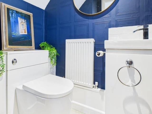 A stylish ground floor WC with modern suite comprising of back to wall WC, vanity basin with bathroom storage and wood-effect tiled flooring.