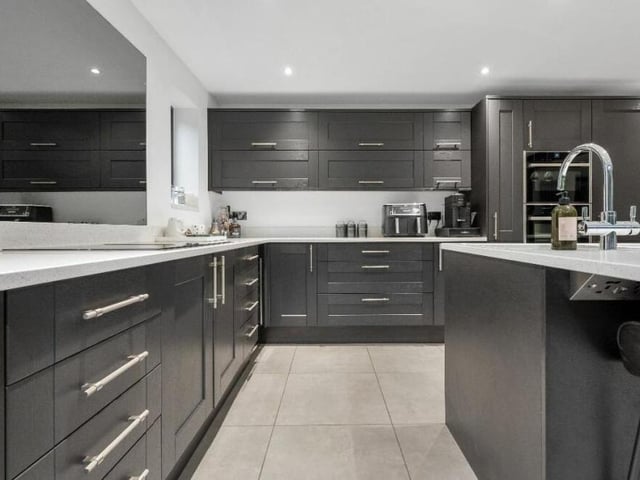 The kitchen is fitted with a range of timeless shaker-style, full-height wall cupboards, base units and drawers, with granite work surfaces over.