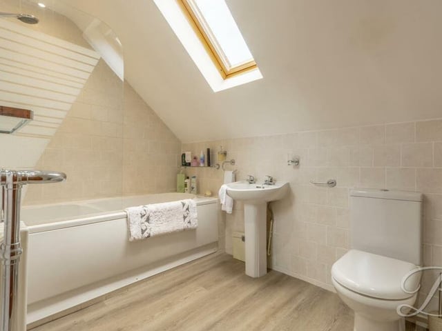 Our last stop on the first floor is the family bathroom, which is a modern three-piece suite in white with neutral-toned tiling. It comprises a panelled bath, low-flush WC, pedestal sink and Velux window.