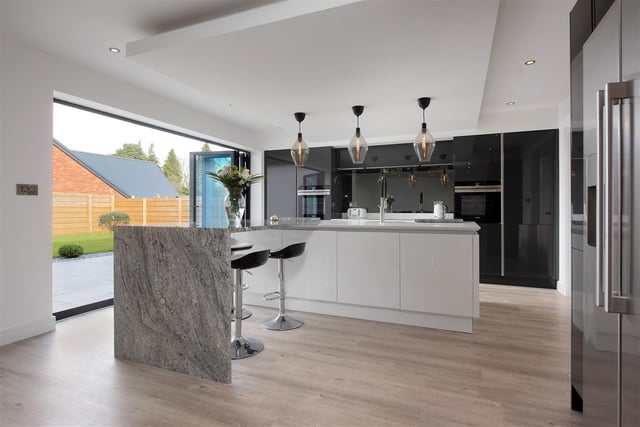 The stunning open-plan family living kitchen boasts a range of contemporary high gloss contrasting cabinets complemented by quartz worktops.  There is an L-shaped island with inset sink.