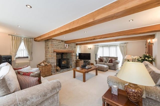 Let's begin our tour of the Linby house in this impressive living room, which is 22 feet in length. It benefits from oak flooring, a large fireplace with a log burner and a window to the front of the property.