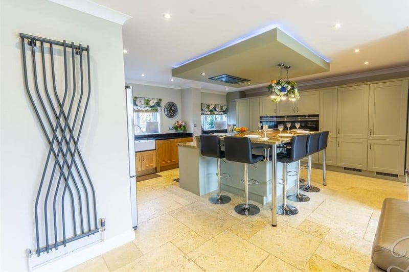 The spacious kitchen from a different angle. It shows an island that has a built-in induction hob with extractor over and built-in breakfast table,