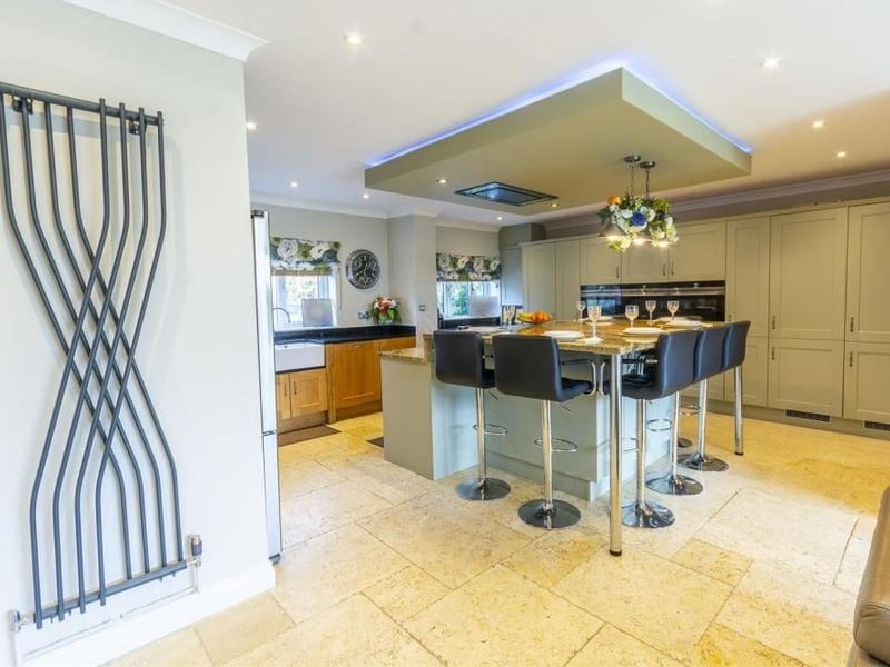 The spacious kitchen from a different angle. It shows an island that has a built-in induction hob with extractor over and built-in breakfast table,