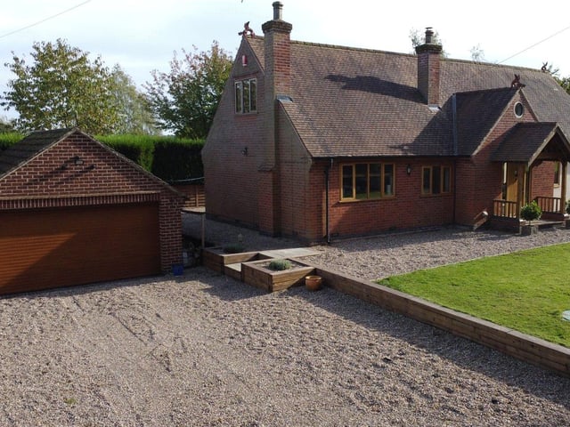 This photo shows how a large, gravelled driveway, which offers off-street parking space, leads to a detached double garage with power and lighting. It also shows the beautifully designed entrance porch to the house.