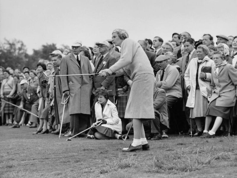 A crowd of spectators watch as Angela Ward Bonallack chips off the fairway on to the 9th green during the 11th Curtis Cup Match golf competition between Great Britain & Ireland and the United States on 21st May 1960 at the Lindrick Golf Club.